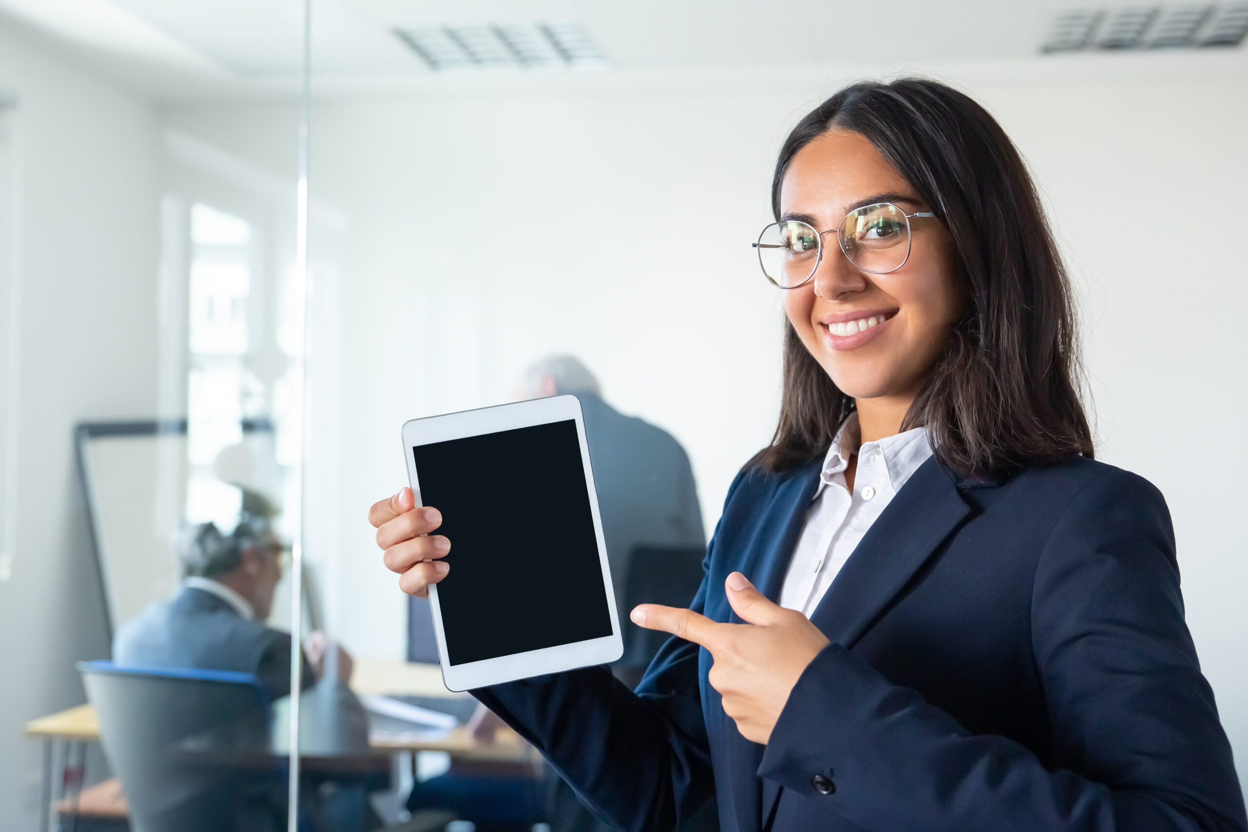 Happy confident business lady holding tablet Happy confident business lady holding tablet, showing and pointing finger at blank screen, looking at camera and smiling. Copy space. Communication and advertising concept